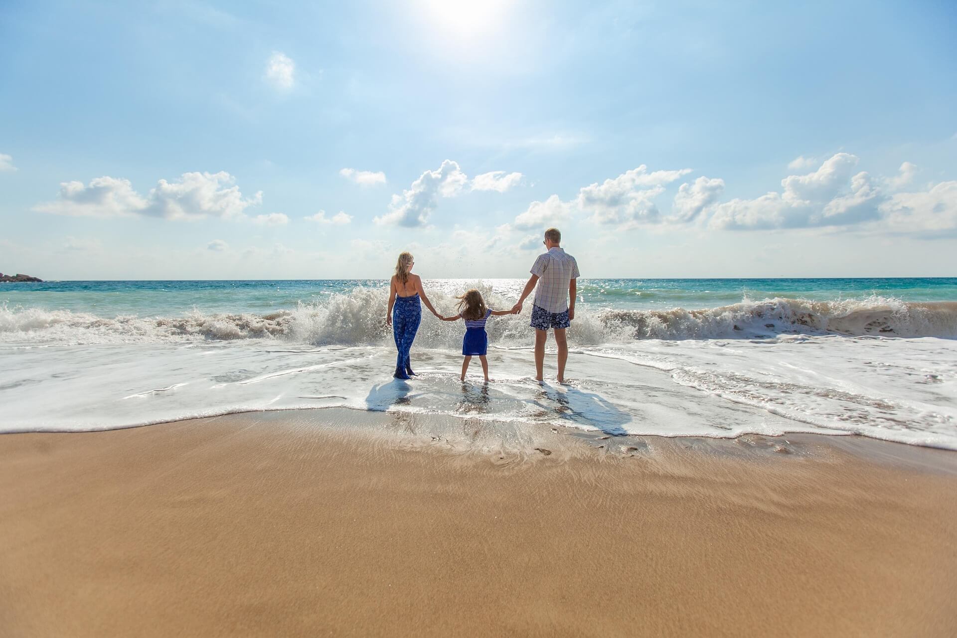Family holding hands at the edge of the ocean